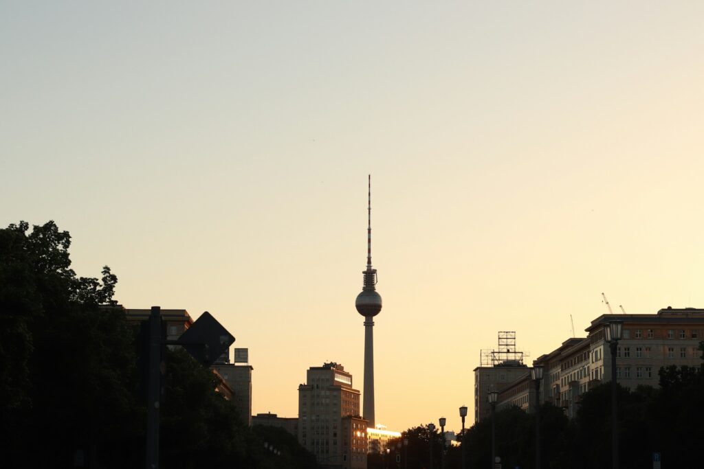 Berlin skyline at dusk with the Fernsehturm TV Tower silhouetted against an orange sunset